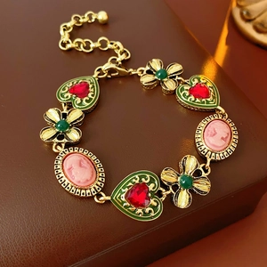 Gros plan d'un bracelet vintage avec émail vert, pierres rouges et breloques camée