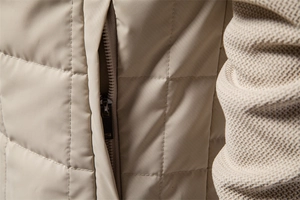 Macro detail of beige quilted jacket featuring metallic zipper pocket and textured fabric