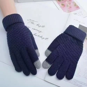 Close-up of navy blue knitted touchscreen gloves with grey fingertips on a flat background