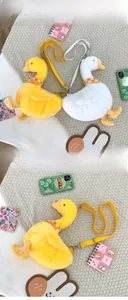 Detail of plush goose and duck crossbody bags featuring checkered scarves and adjustable straps