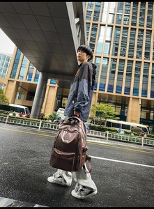 Uomo con zaino vintage in pelle PU marrone scuro in una moderna scena di strada urbana