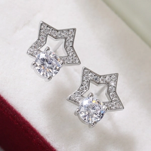 Macro shot of star-shaped cubic zirconia stud earrings resting on white velvet