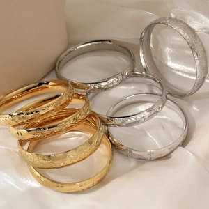 Wide vintage stainless steel engraved bracelets in gold and silver on silk background