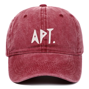 Detailed close-up of white APT. letter embroidery on washed dark red vintage baseball cap