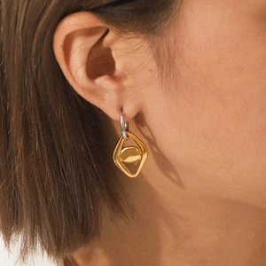 Minimalist bicolor stainless steel geometric hoop earrings worn by a female model