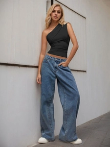 Slim fit black one shoulder top paired with blue wide leg jeans on street style model