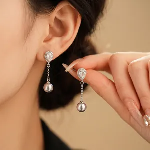Elegant pear-cut zircon and silver-grey pearl drop earrings worn by a model