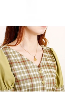Dettaglio di una collana con ciondolo a quadrifoglio dorato indossata da una modella