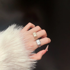 Detail of gold and silver watch-shaped rings with sparkling zircon pavé on model's hand