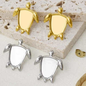 Detail of minimalist turtle studs in gold and silver finish on a textured stone base