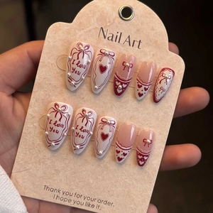 Detailed view of almond nails with pearls, red hearts and bow accents for Valentine's