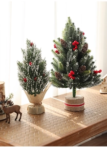 Close-up of mini snow-flocked Christmas trees with red berries and burlap bases