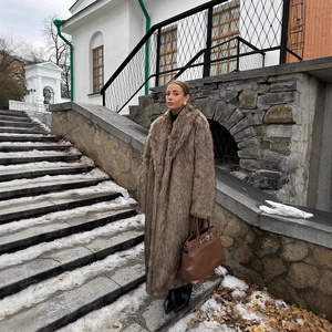 Elegant long brown faux fur coat for women, warm winter style worn with chic leather handbag