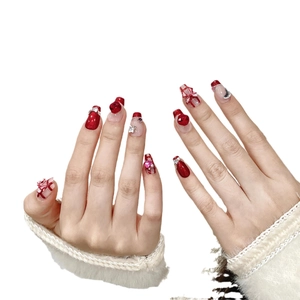 Unghie finte fatte a mano rosse e bianche con strass a cuore rosso e fiocchi