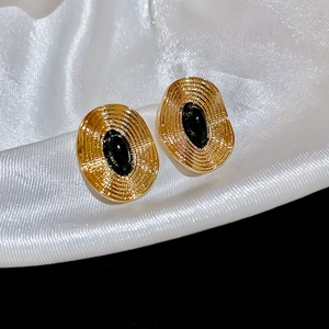Makroaufnahme der ovalen Vintage-Ohrstecker mit schwarzem Tropföl und goldener Spiralstruktur