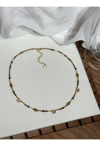 Detail of beaded necklace with gold tubes, tiger eye stones and heart pendant