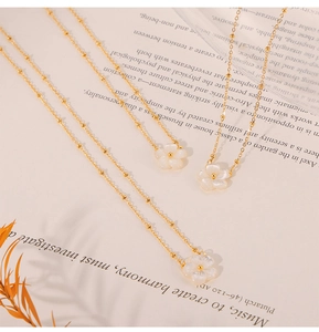 Elegant 18K gold plated necklace featuring a white shell flower pendant on a book