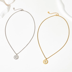Detailed view of moon and star pendants in silver and gold tone on stainless steel chains