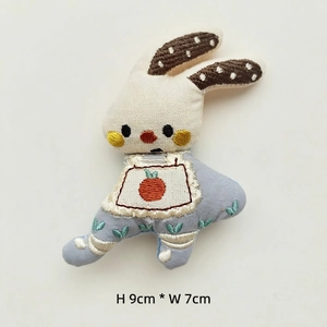 Detailed embroidery on white fabric rabbit doll with carrot bib measuring 9cm by 7cm