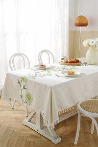 Detailed view of cream waterproof tablecloth with green embroidery and fringe edges