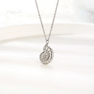 Elegant 18K gold conch shell pendant necklace displayed on a white ceramic plate