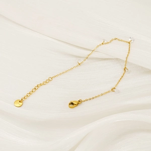 Detail of gold stainless steel chain bracelet featuring five clear zircon stones on silk