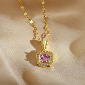 Gold titanium steel necklace with an octagonal pink gemstone pendant on beige cloth