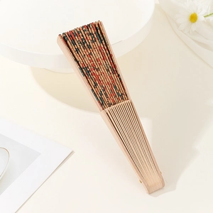 Folded Portuguese cork hand fan with floral texture patterns on a beige background
