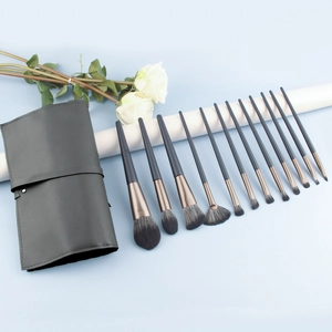 12-piece professional makeup brush set with dark grey handles and a black leather travel wrap
