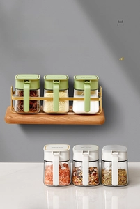 Close-up of 6 glass spice jars with colorful lids on a two-tier gold metal storage rack