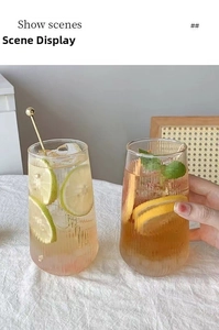 Close-up of vertical ribbed glass tumblers with lemon slices and golden stir stick