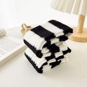 Close-up of thick knitted white striped leg warmers with cozy winter texture