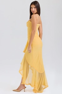 Detail view of the yellow ruched dress featuring asymmetric ruffled hem and slim straps