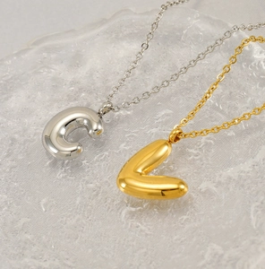 Close-up of shiny gold and silver bubble letter pendants on delicate steel chains