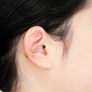 Close-up of triple-layered gold ear cuff with beaded and chain textures on ear