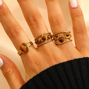 Three-piece stainless steel ring set with tiger eye stones worn on model's hand