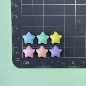 Close-up of colorful resin star charms on a measurement mat for DIY nail art and jewelry