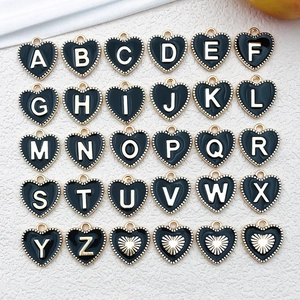 Flat lay of 30 black enamel heart pendants with gold A-Z letters for jewelry making
