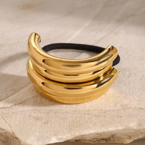 Close-up of polished gold-plated double arc metal ponytail cuff on stone surface