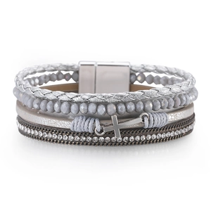 Detail of multi-layer woven bracelet featuring a silver cross charm and magnetic clasp