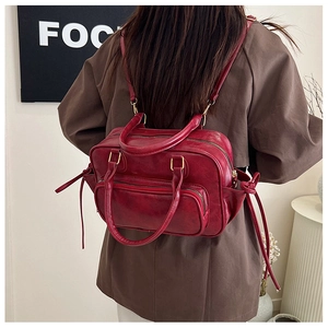 Detail view of red glossy synthetic leather backpack with golden metal zippers and handle