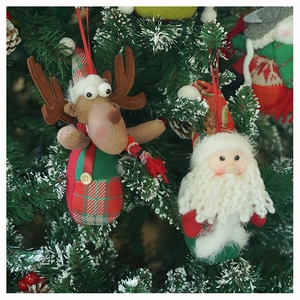 Close-up of plush Santa and Reindeer hanging ornaments on a snowy Christmas tree branch