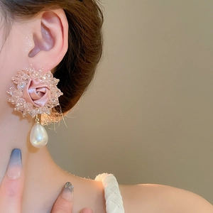Detail of pink fabric rose earring with crystal trim and a drop pearl on a model