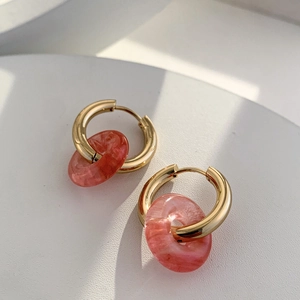 Detailed macro view of 18K gold-plated hoops featuring pink marble-textured round pendants