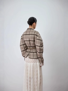 Vue arrière d'une veste marron à carreaux et jupe en dentelle blanche au style minimaliste