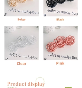 Detail view of large rose flower hair claws in cream, black, clear, and pink matte finishes