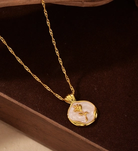 Detail of a golden rose embossed on a pearl white shell pendant with a twisted chain