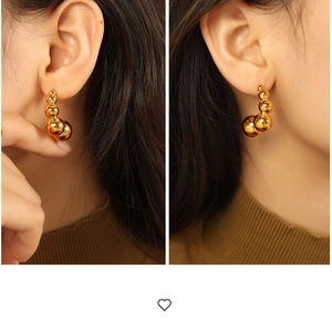 Detail view of exaggerated gold pea earrings with five polished spheres in a curved design