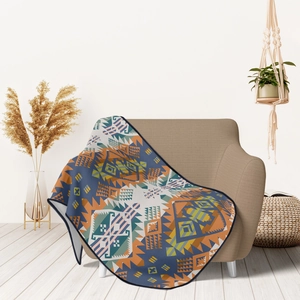 Detail of colorful geometric flannel throw blanket draped over a cozy fabric sofa