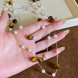Tiger eye and pearl beaded layered necklace with elegant gold chain in hand